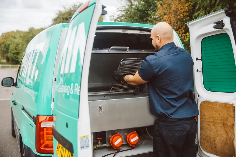 Taylor loading an oven rack into the cleaning tank in the MINT van
