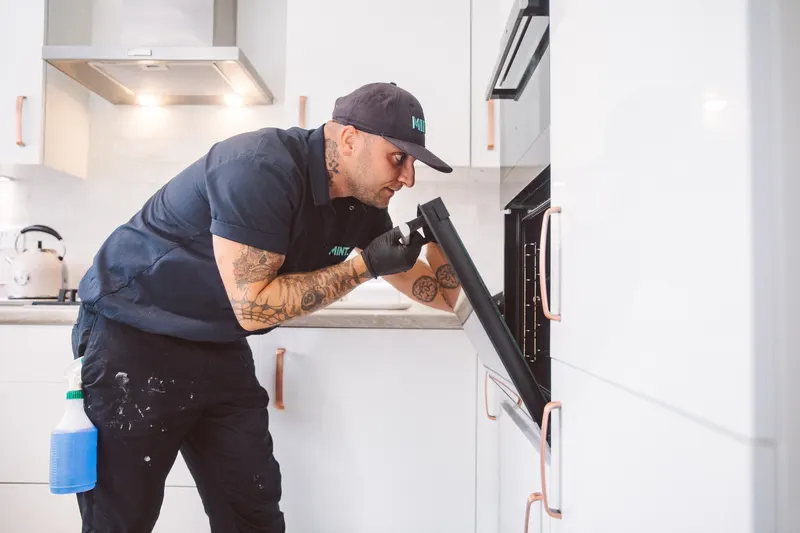 Taylor inspecting an open oven during a clean