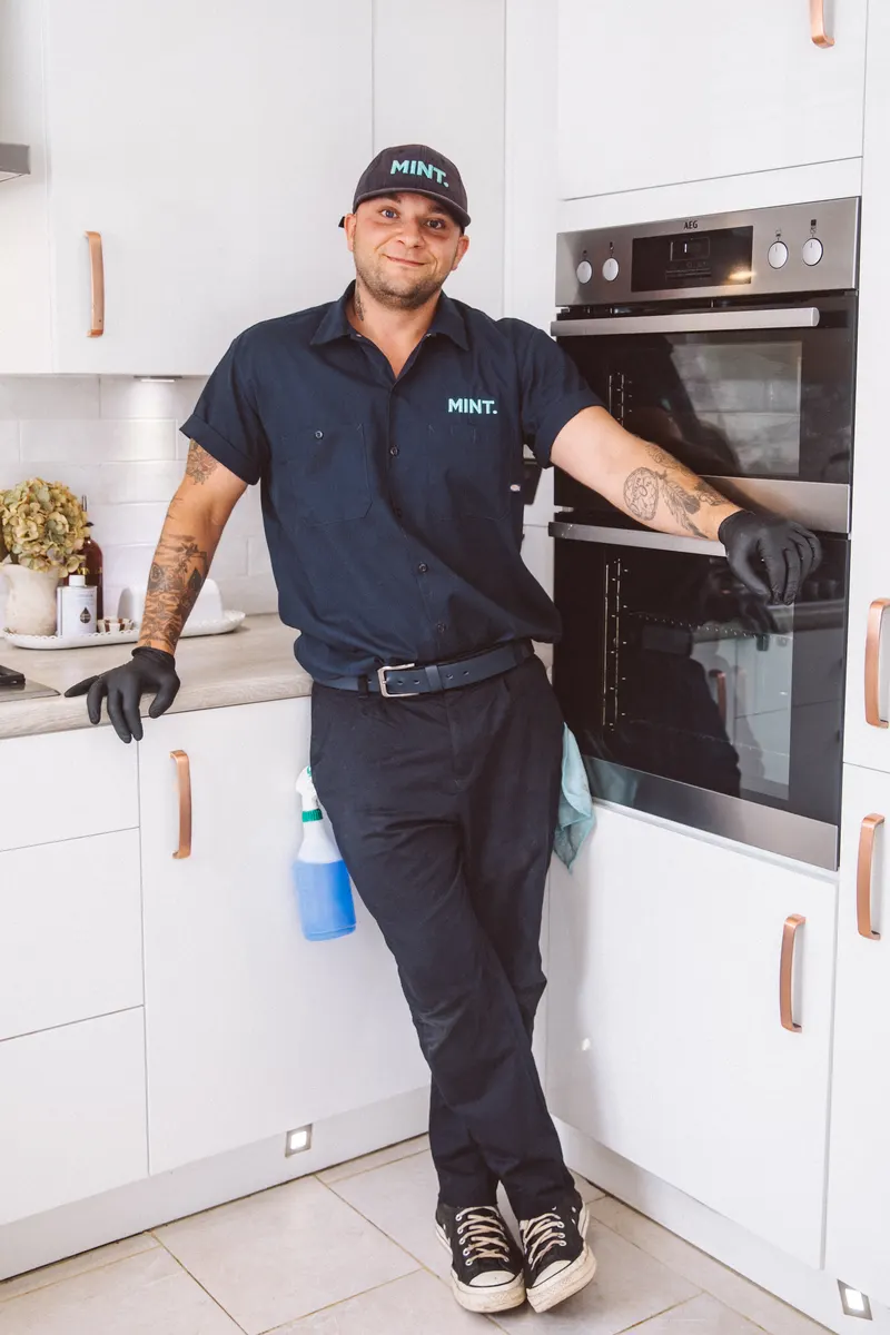 Taylor in his MINT uniform standing beside an oven in a kitchen