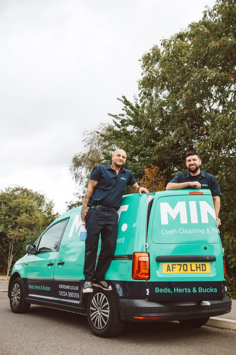 Taylor and Sam smiling beside the back of the MINT van