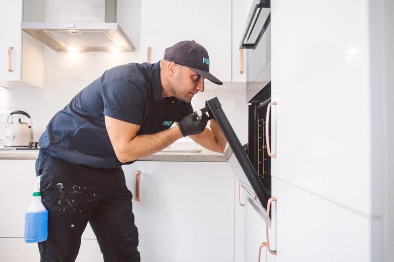 Taylor inspecting an open oven during a clean