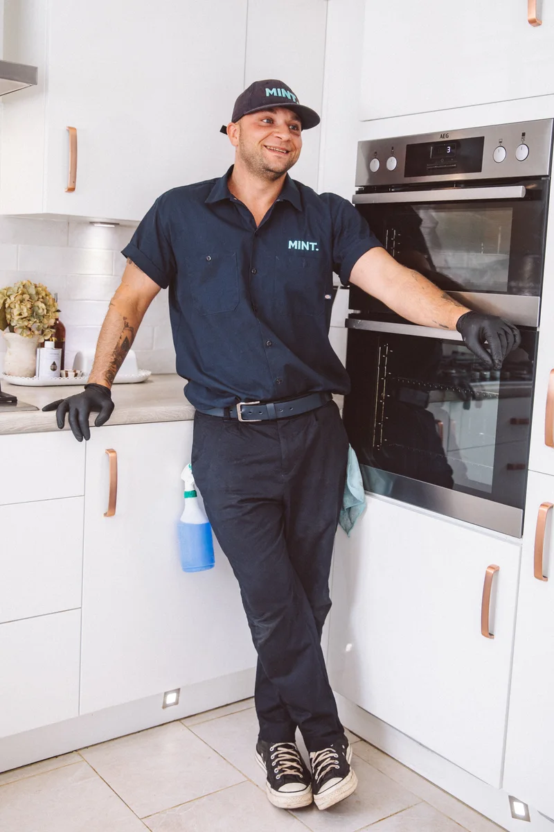 Taylor Wilson, the MINT oven cleaner, standing beside an oven